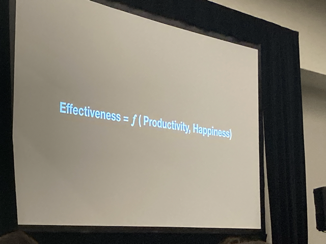 Slide of white text on black background stating Effectiveness = f(Productivity, Happiness)