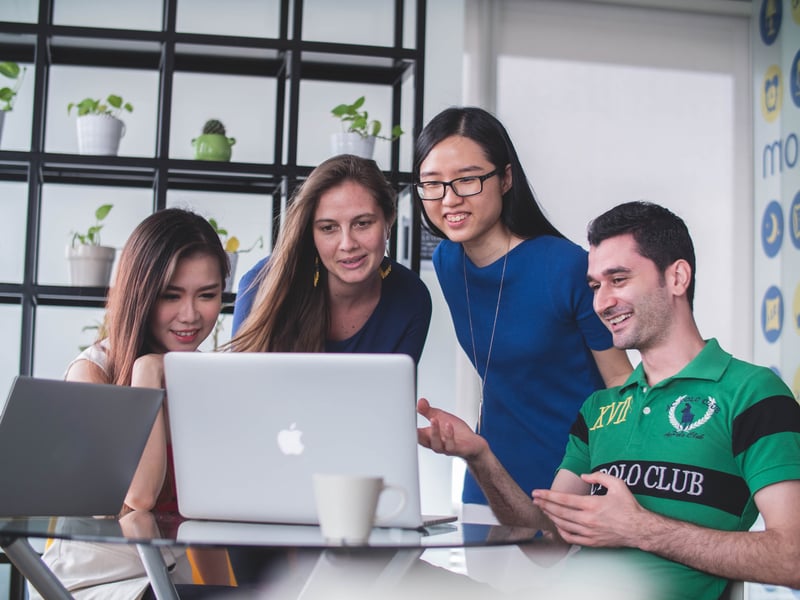 4 people looking at laptop