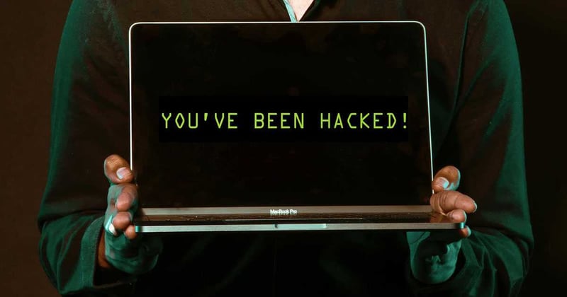 Someone holding a laptop with 'You've been hacked!' displayed upon the screen